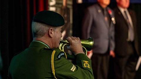Picture shows a man in military uniform playing trumpet at a dawn service.