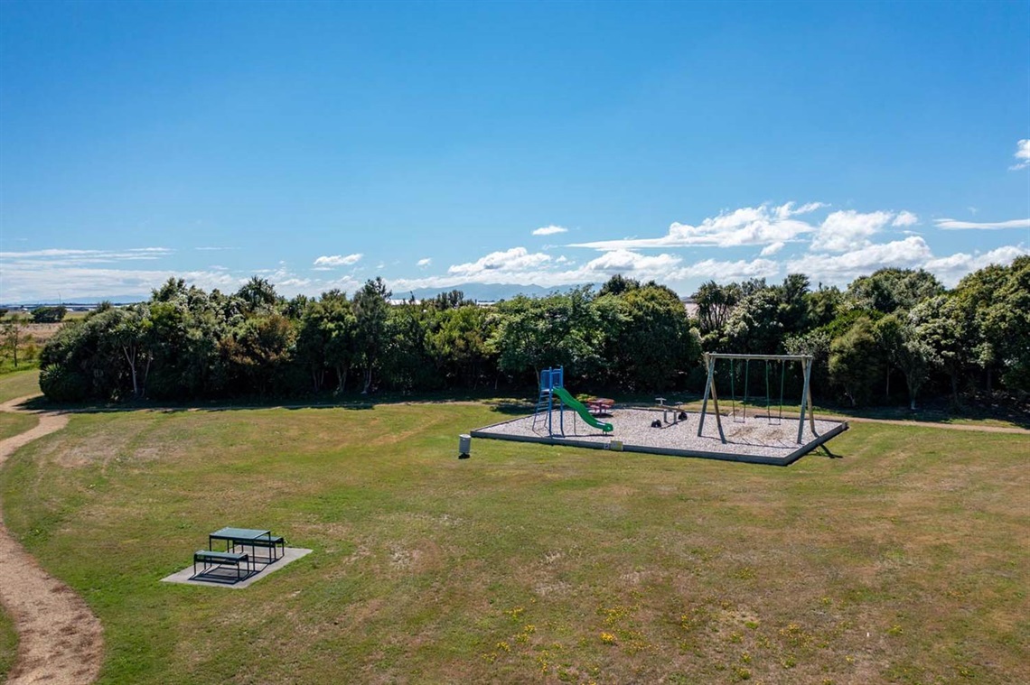 Picture show play equipment and a picnic table on grass