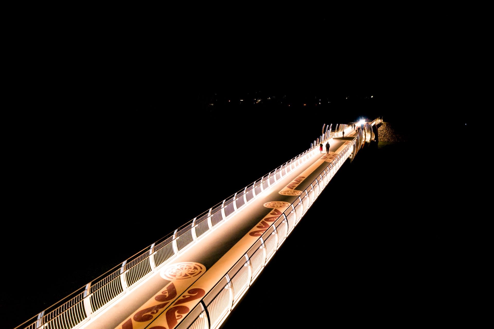 Painted patterns on completed bridge, lit up at night.