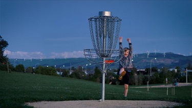 A gleeful child celebrates getting his frisbee in the disc golf 'hole'. 