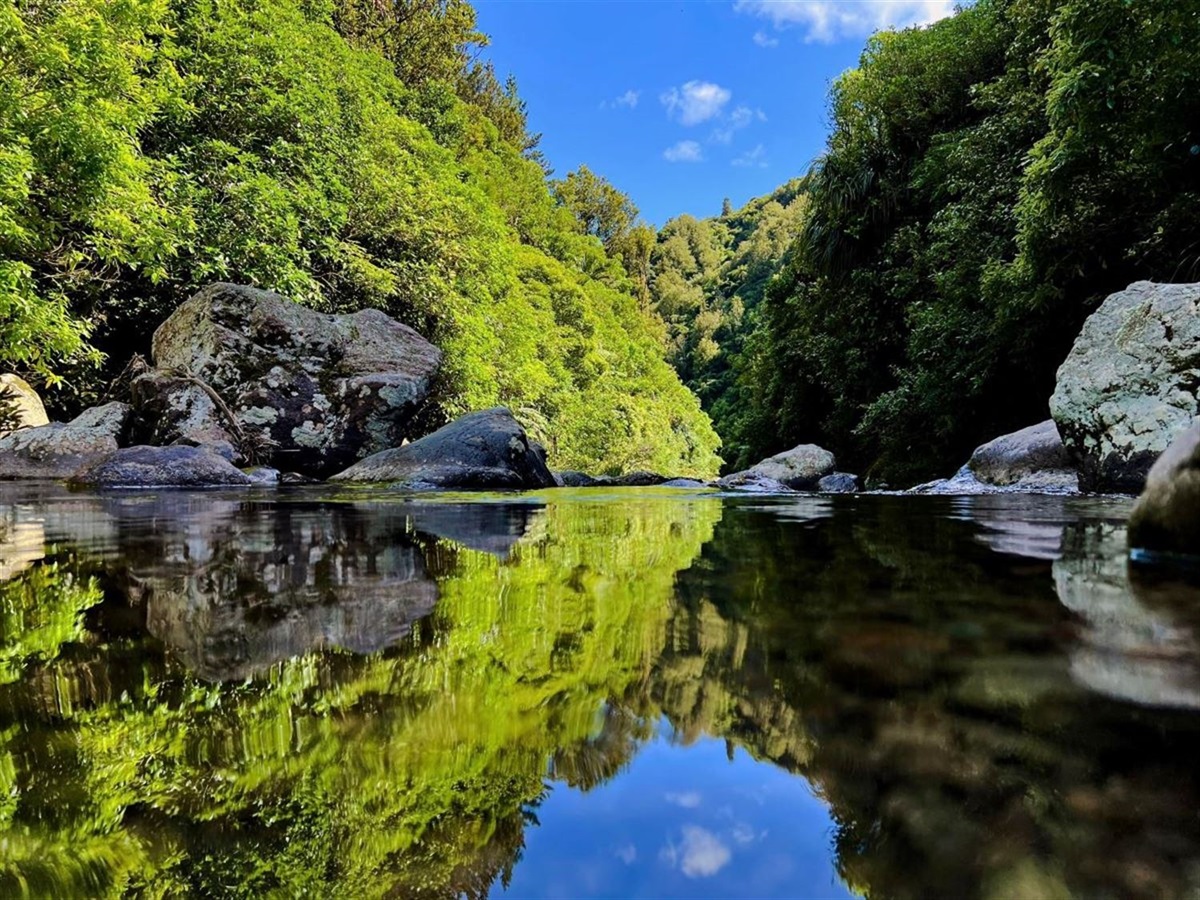 Image of a pond reflecting the blue sky and mountains around it