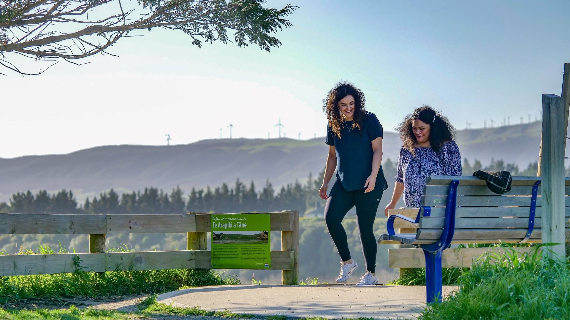 2 young women smile as they reach the top of the steps.
