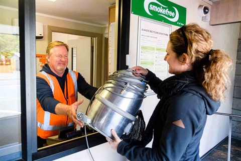 Photo shows woman handing over an old vacuum cleaner to a worker at the Ferguson Street recycling centre. 