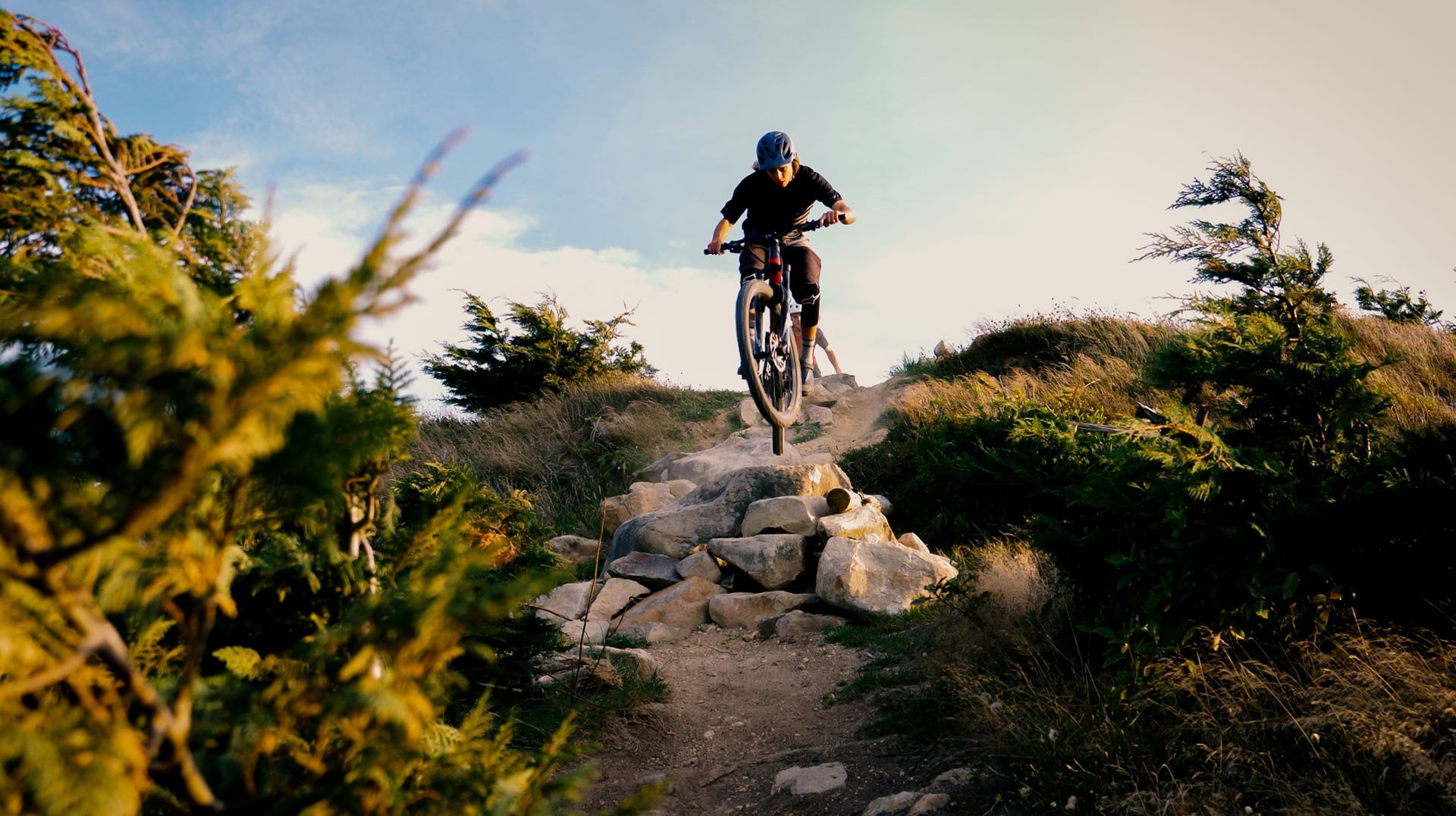 Young man riding mountainbike down a gnarly trail with lots of rocks.