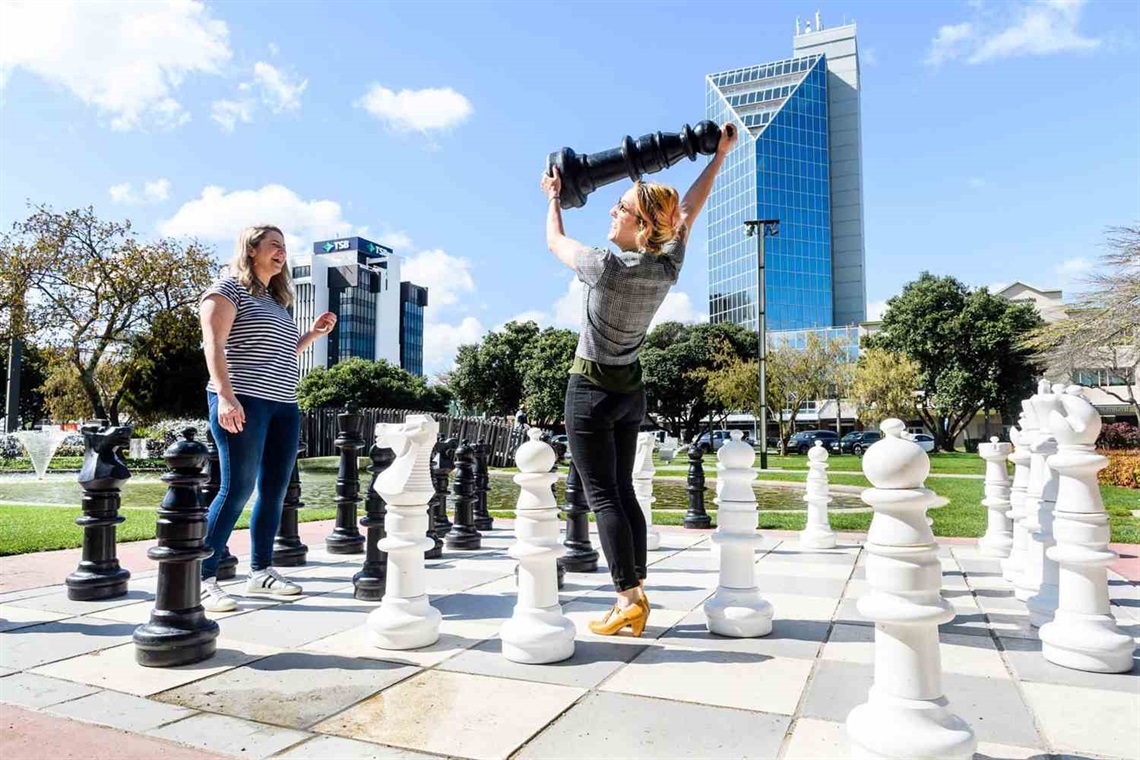Two young adults playing giant chess in Te Marae o Hine.