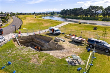 Four workers are dwarfed by the large hole they've dug on the riverbank.