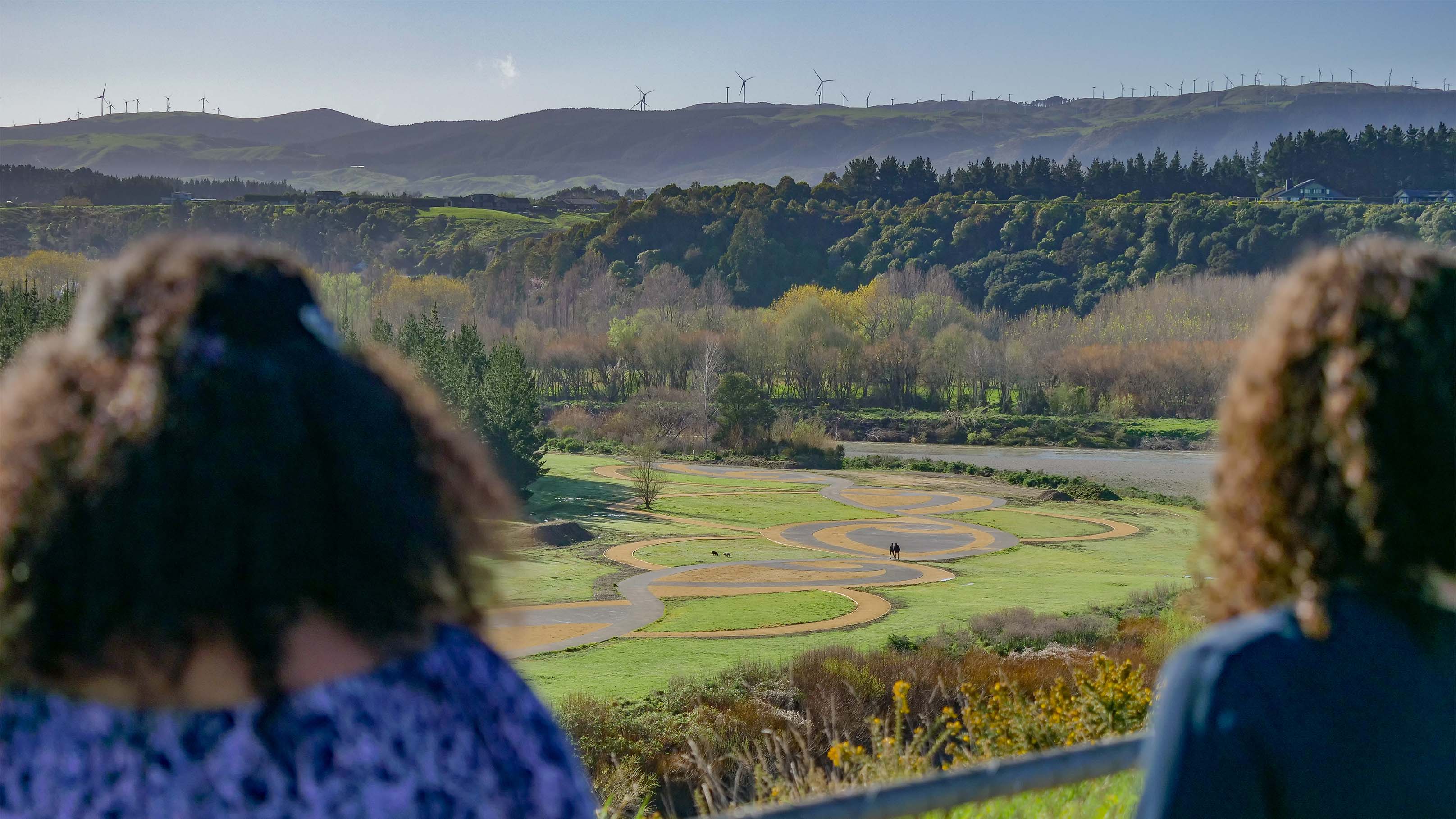 Photo shows two women with their backs to the camera looking out at the view over the river from Anzac Park.