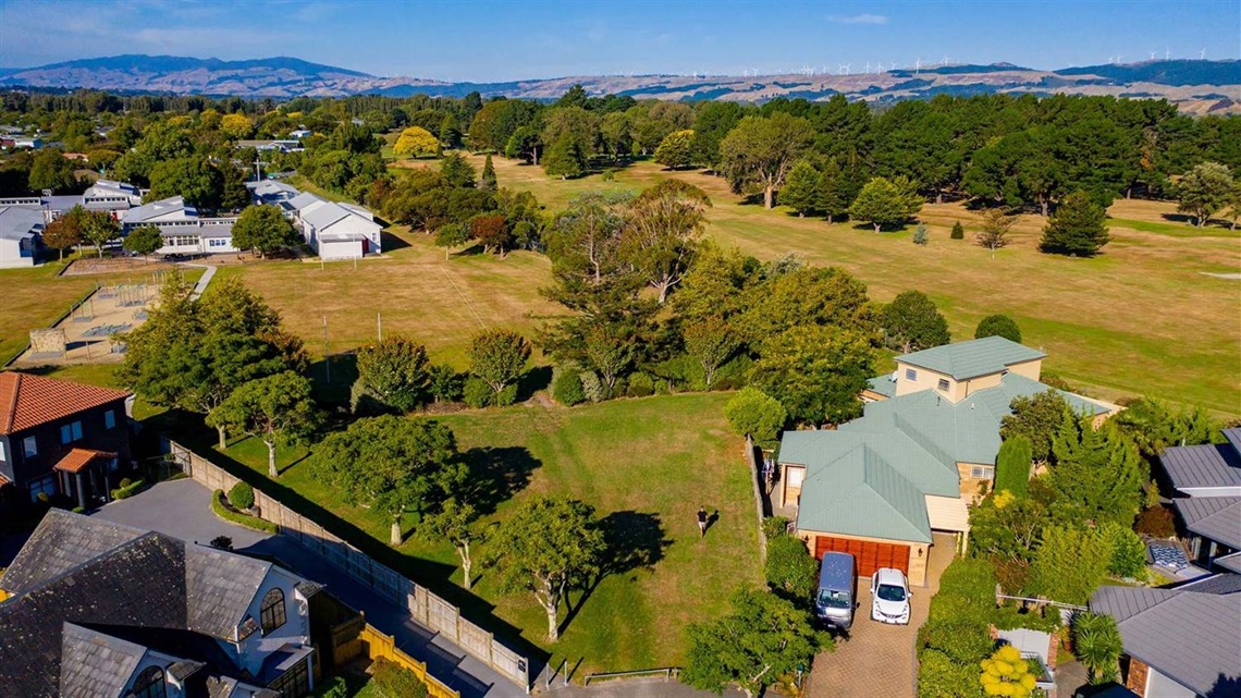 Photo shows small grassed area surrounded by leafy trees.