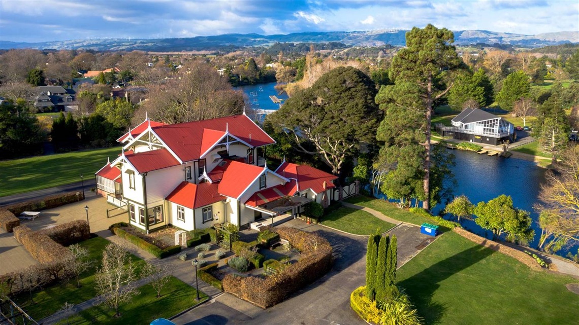 Photo shows historic Caccia Birch homestead with its manicured grounds and the lagoon in the background.