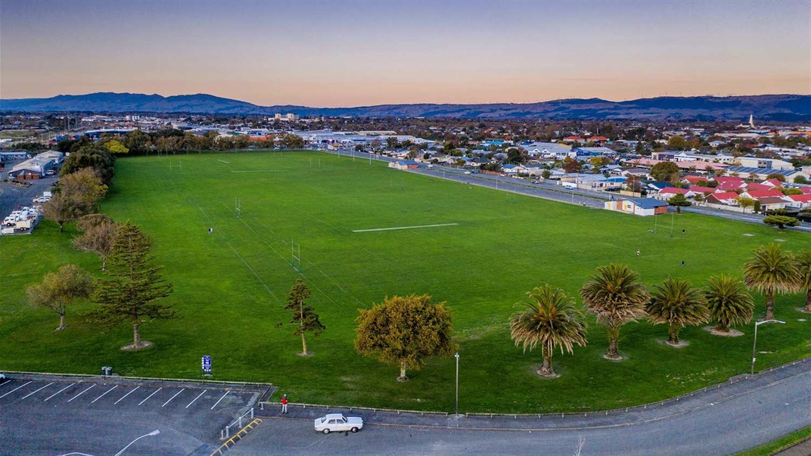 Photo shows aerial view of sportsfields with palm trees in the foreground.