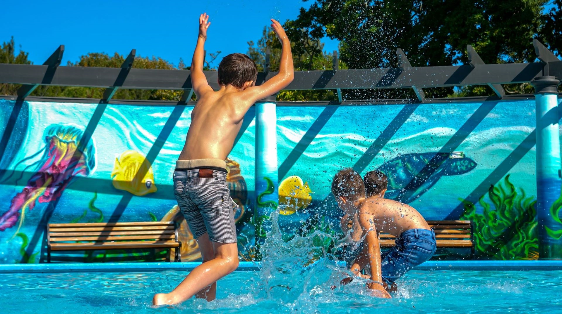 Children splashing each other at the pool.