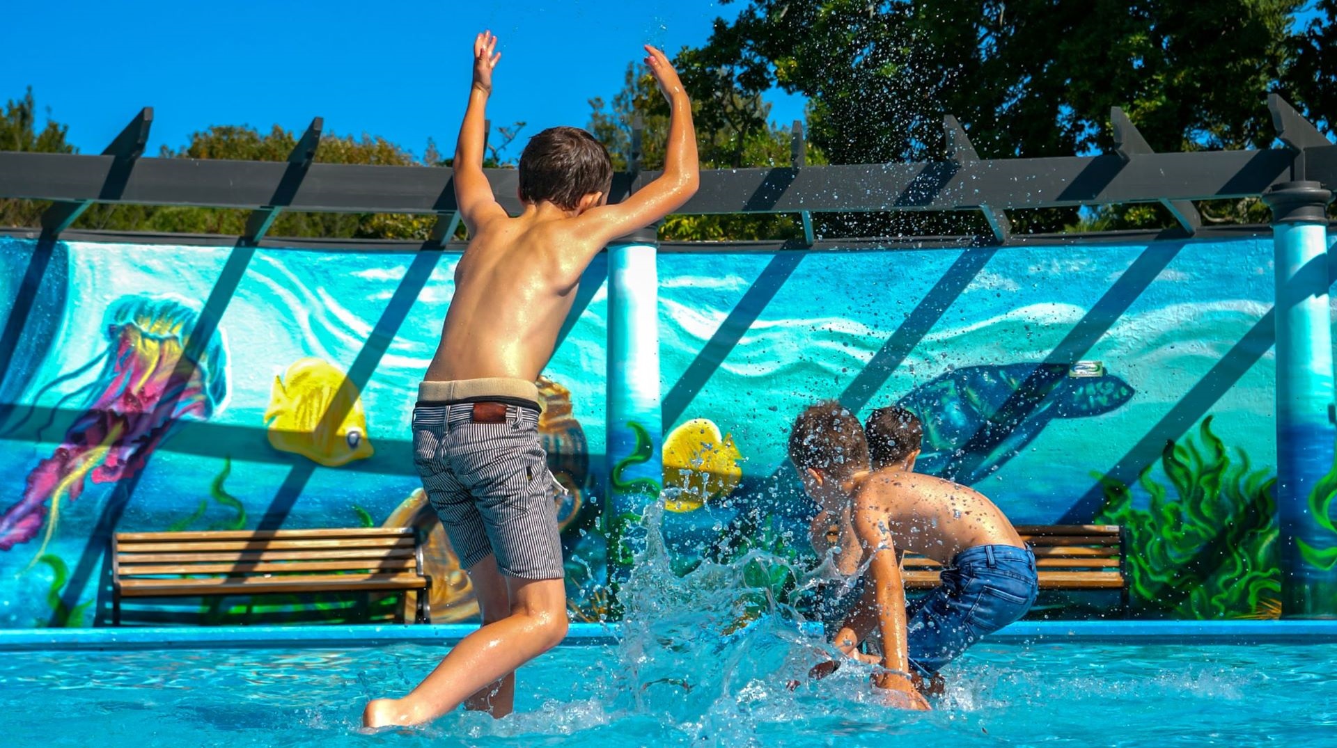 Photo shows children splashing each other at the pool.