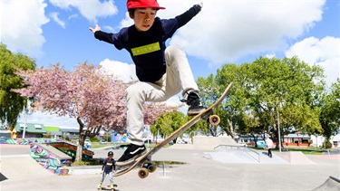 Skateboarding in full flight on one of the skatepark jumps.