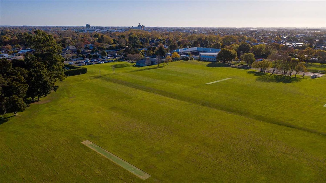 Photo shows sportsfields surrounded by trees.