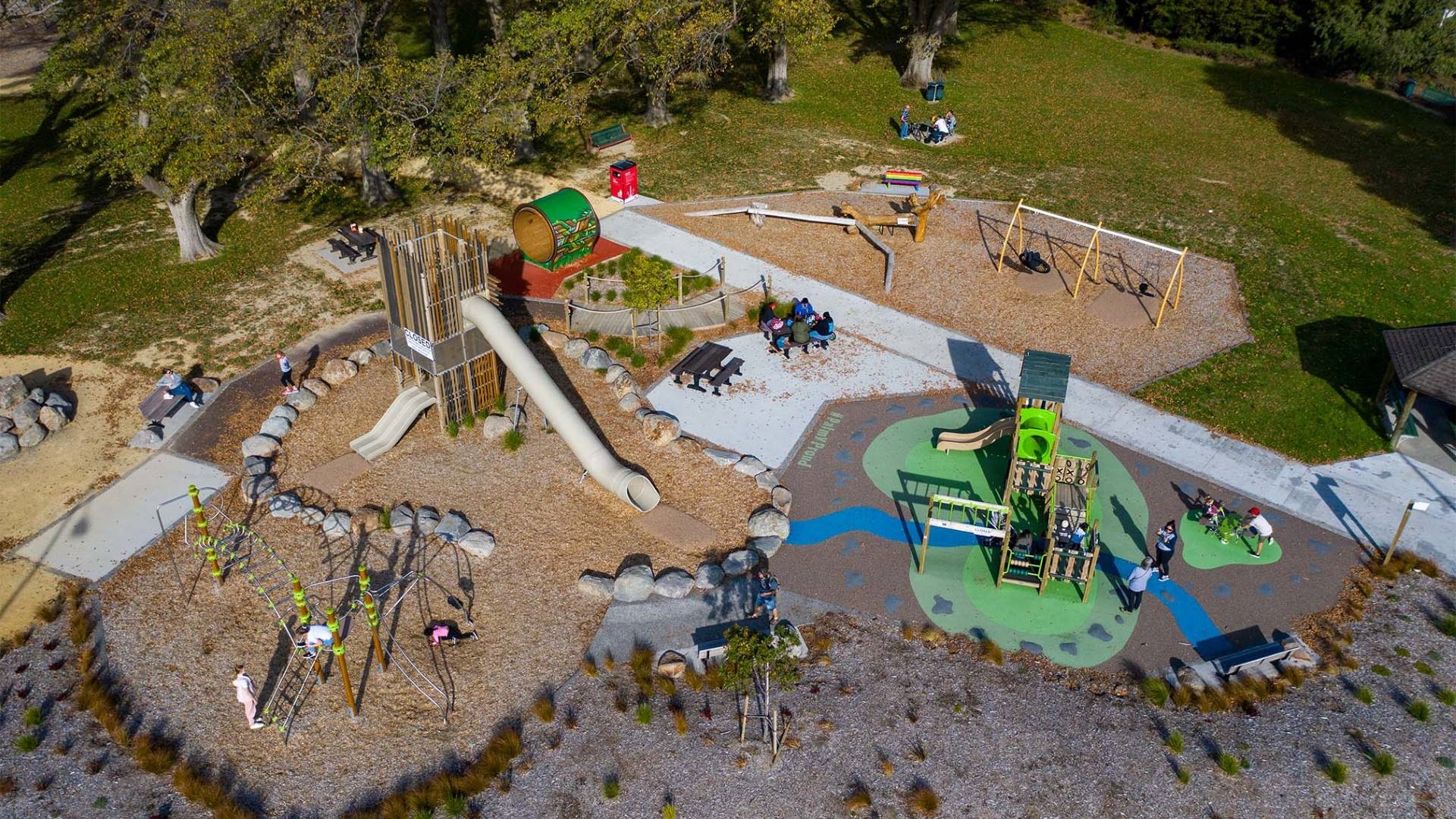 Photo shows aerial view of park with lots of shade trees, new native plants, a grassed area and an awesome destination playground.