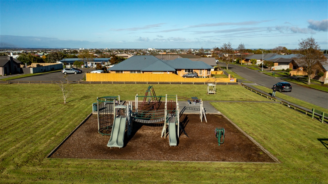 Photo shows the play equipment and picnic tables at the playground.