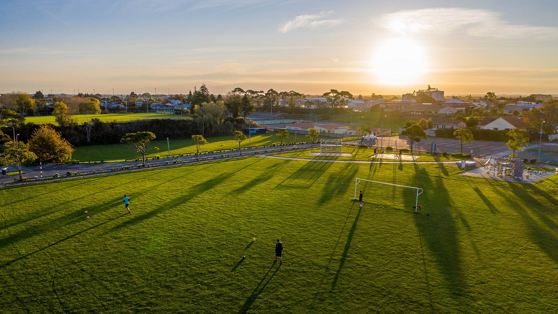 Photo shows aerial view of sportsfields and a small playground neighboured by a reserve.