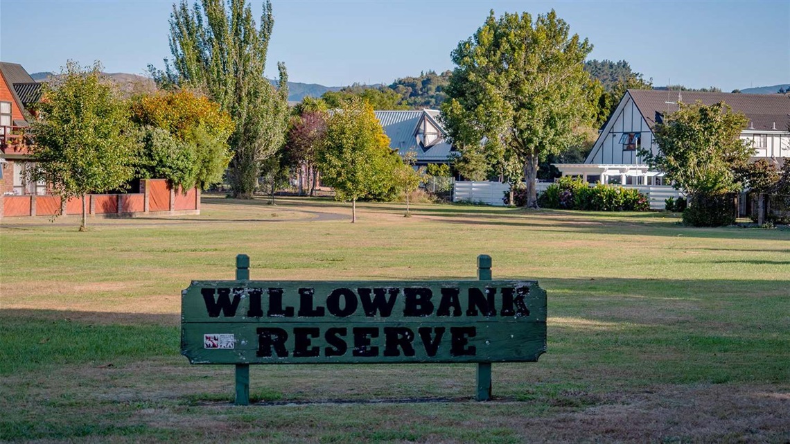 Photo shows a small flat roadside reserve with a sign on it that says 