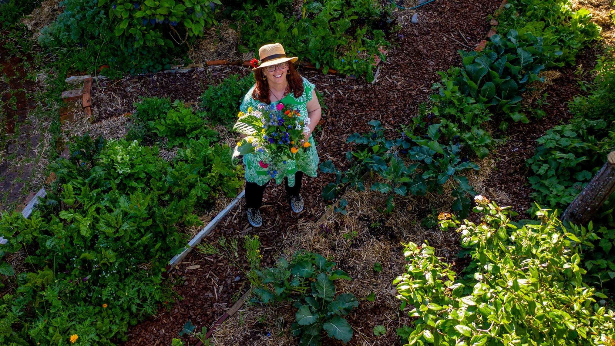 Photo shows keen gardener Helen Lehndorf standing in her garden at home, among rows of mulched beds full of vegetables, herbs and flowers.