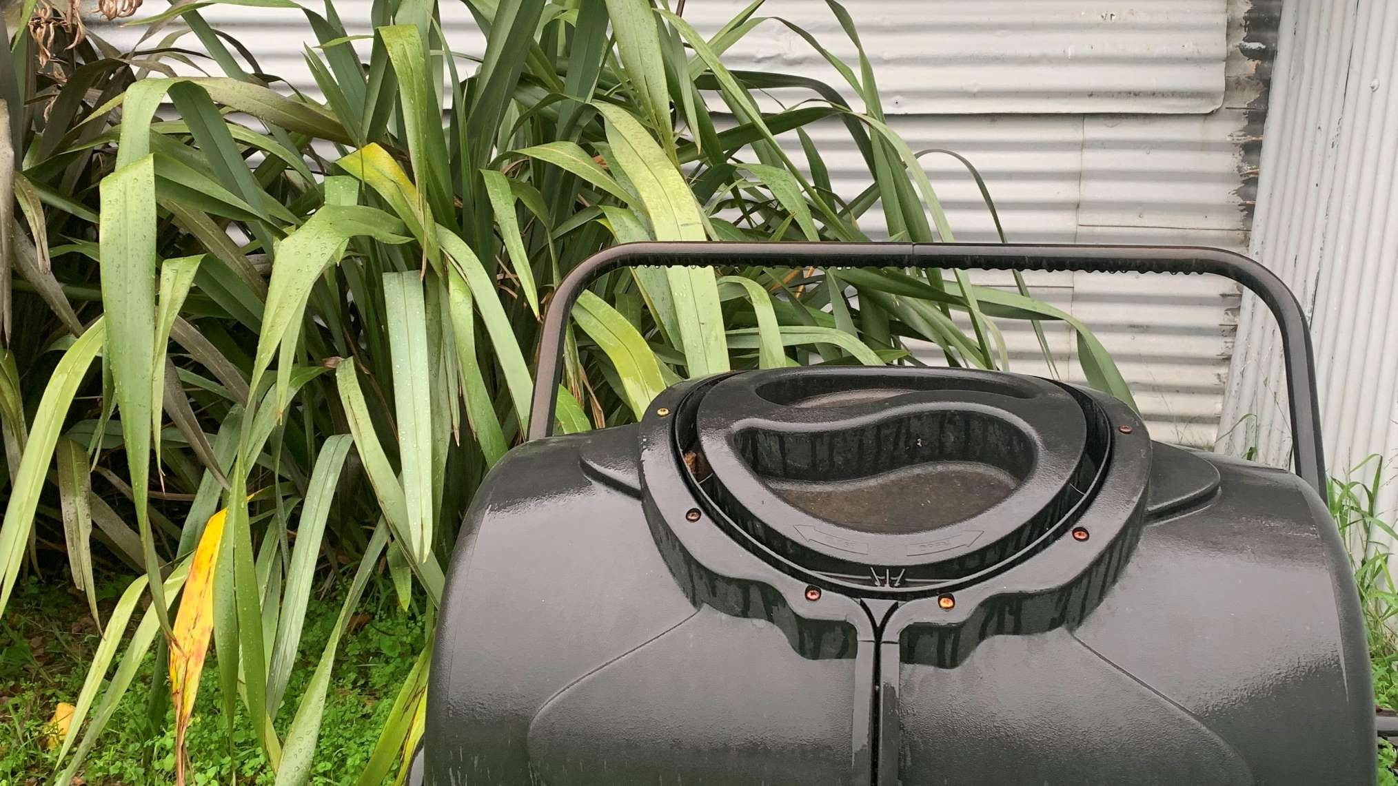 Photo shows rotator compost bin and flax bushes in a Palmy back yard.